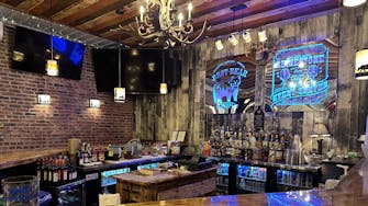 Close-up of a glittering rhinestone bar sign above shelves of alcohol.
