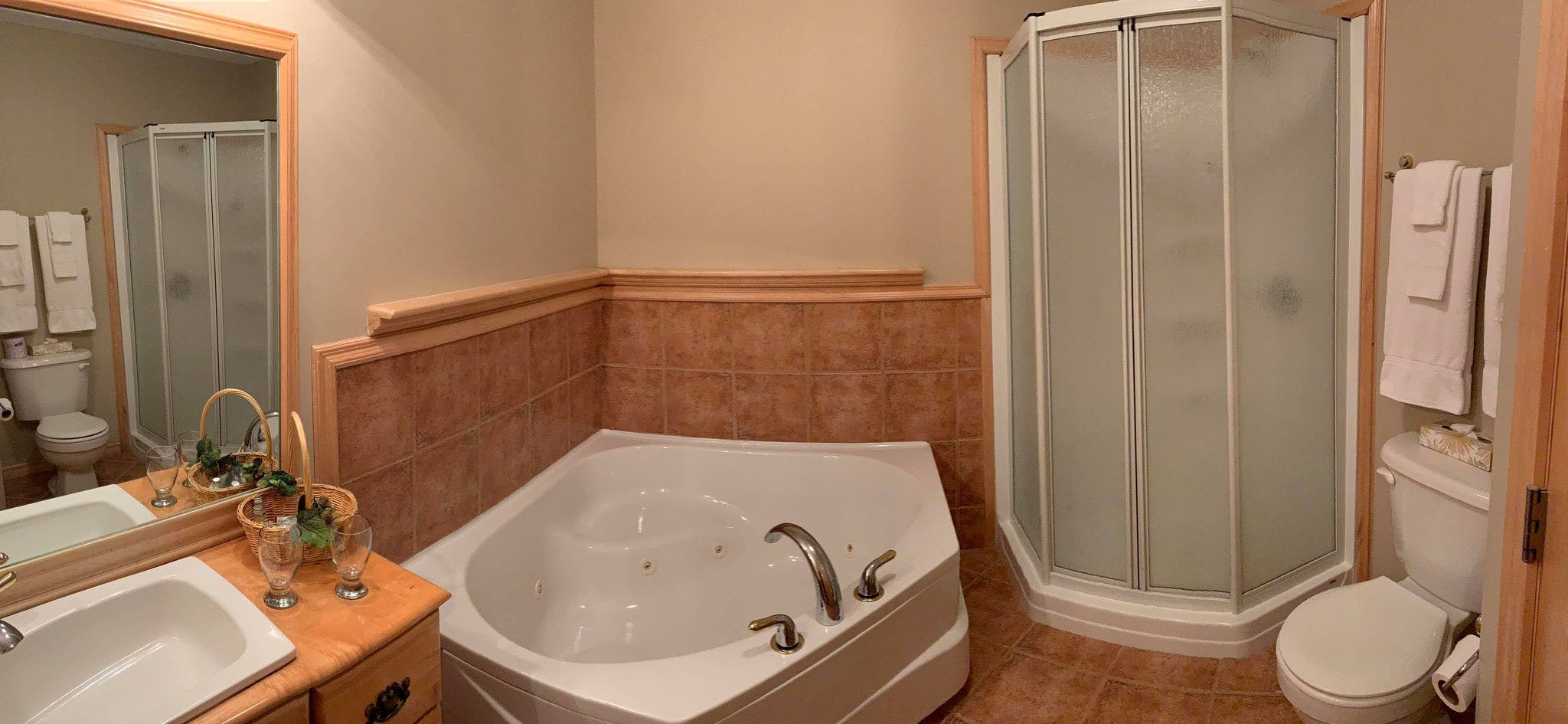 Salle de bain de la chambre Erable avec bain tourbillon et douche debout.