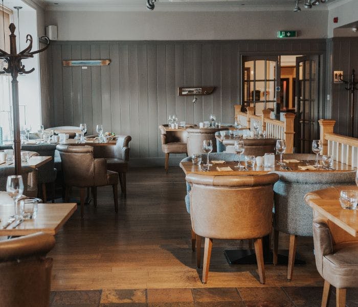 A cosy restaurant with rustic wooden tables and chairs, creating a warm and inviting atmosphere.