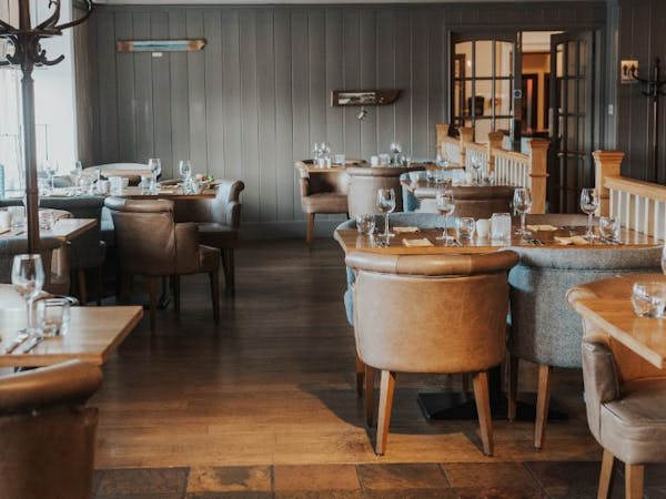 A cosy restaurant with rustic wooden tables and chairs, creating a warm and inviting atmosphere.