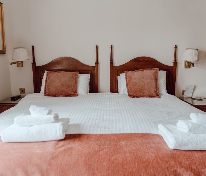 A cosy bed with crisp white sheets and a warm red throw creating a soothing and inviting ambiance.