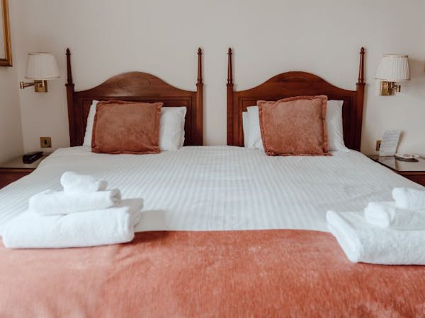 A cosy bed with crisp white sheets and a warm red throw creating a soothing and inviting ambiance.