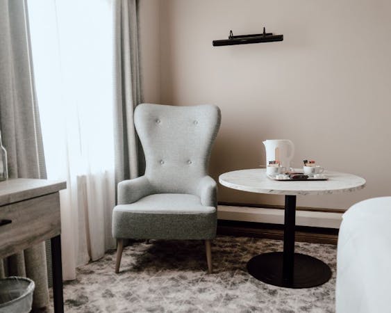 Hotel room setup with a chair and table, providing a comfortable space for guests to unwind or work.