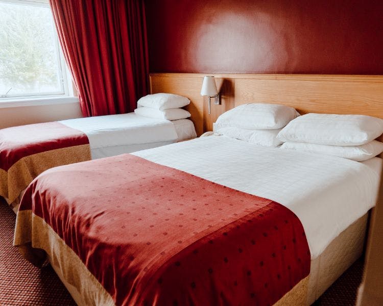 Family room with. double and single bed with vibrant red walls and matching furnishings.