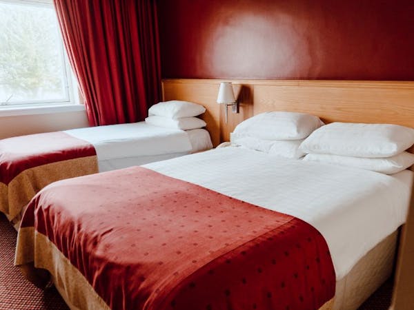 Family room with. double and single bed with vibrant red walls and matching furnishings.