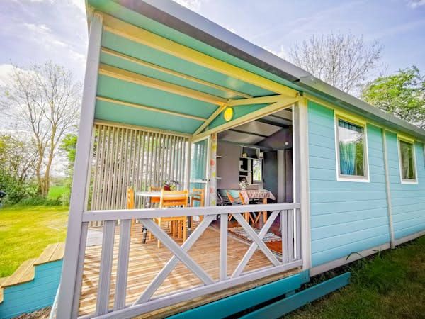 Vue extérieure du chalet bleu sur sa terrasse.