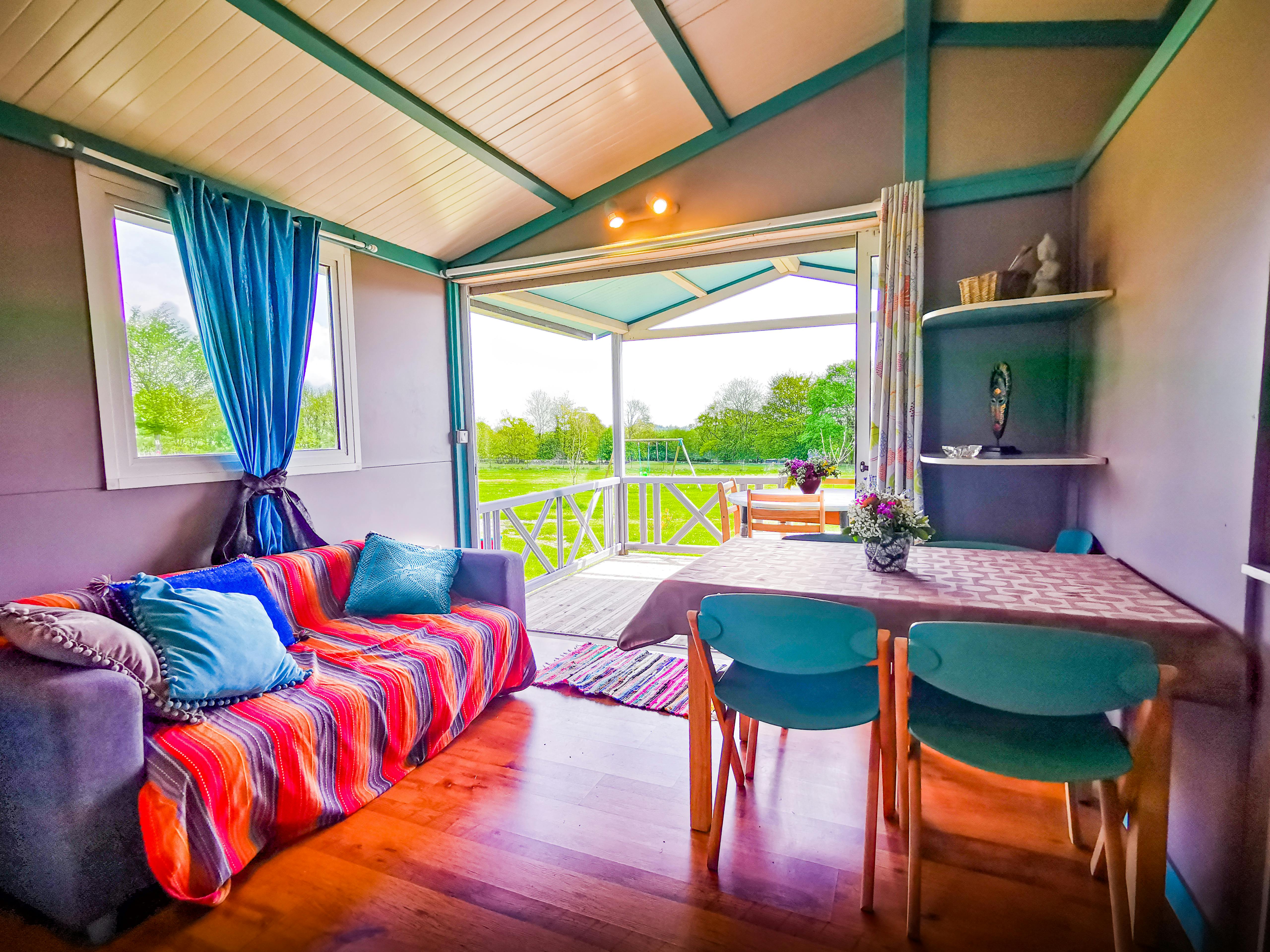 Intérieur du chalet vue du salon/salle à manger vers jardin et terrasse.