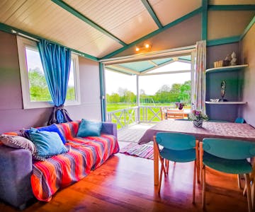 Intérieur du chalet vue du salon/salle à manger vers jardin et terrasse.