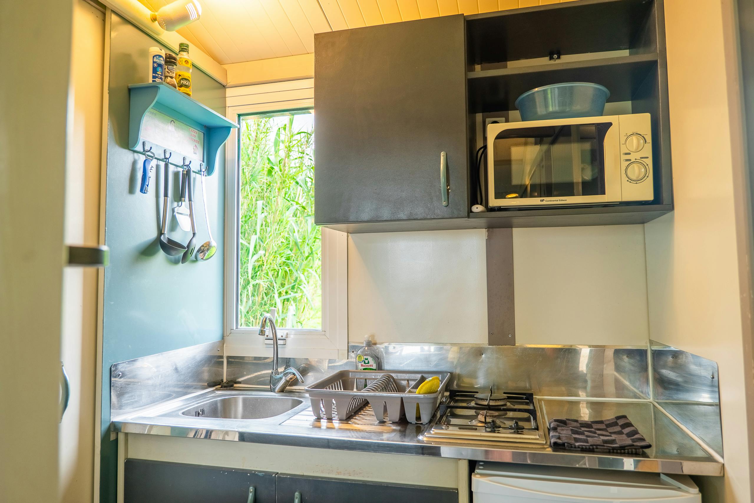 Au-Bonheur-Nomade - vue intérieure de la cuisine équipée avec plaque, réfrigérateur, micro-onde.