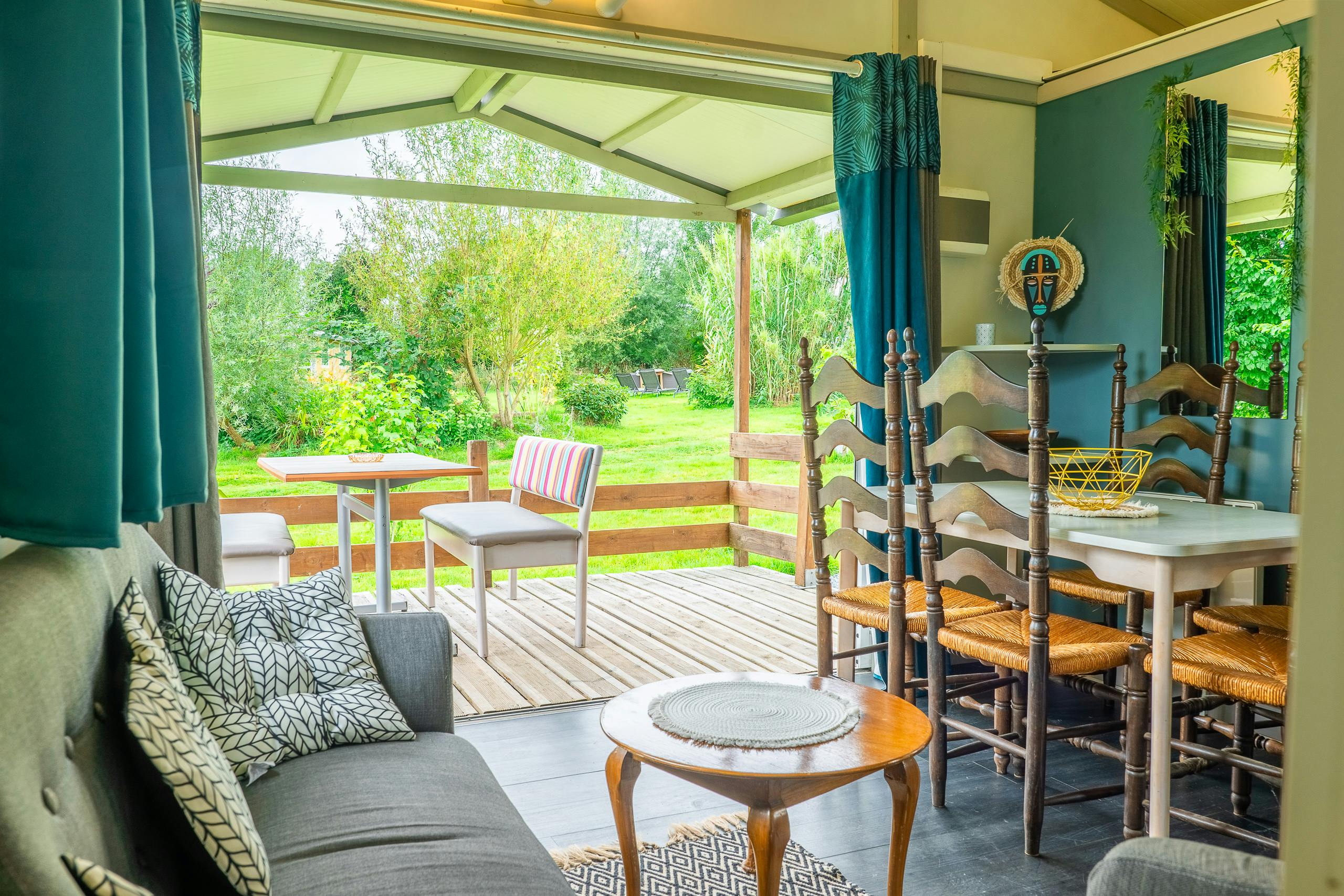 Au-Bonheur-Nomade - vue intérieure du salon et de la salle à manger du chalet marron vers l'extérieur du domaine. Terrasse