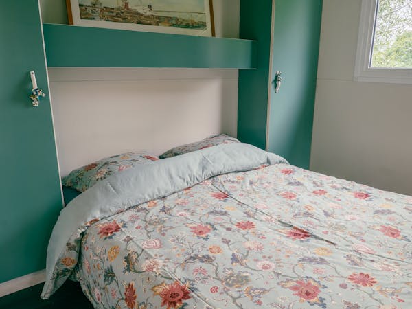 Au-Bonheur-Nomade - vue intérieure de la chambre parentale du chalet marron. Lit double avec rangement