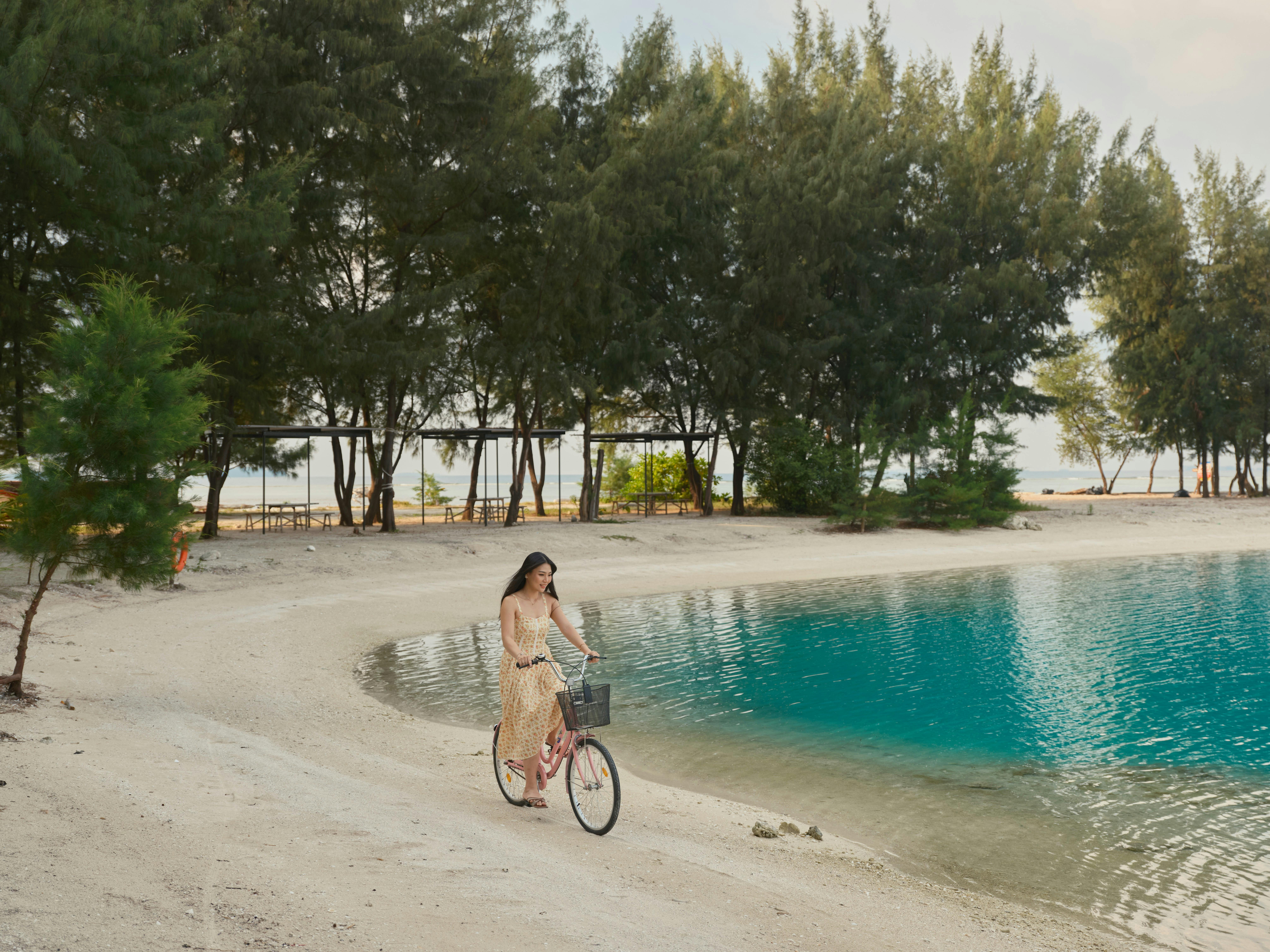 Girl rides bike along beachfront in Pulau Payung in Thousand Islands