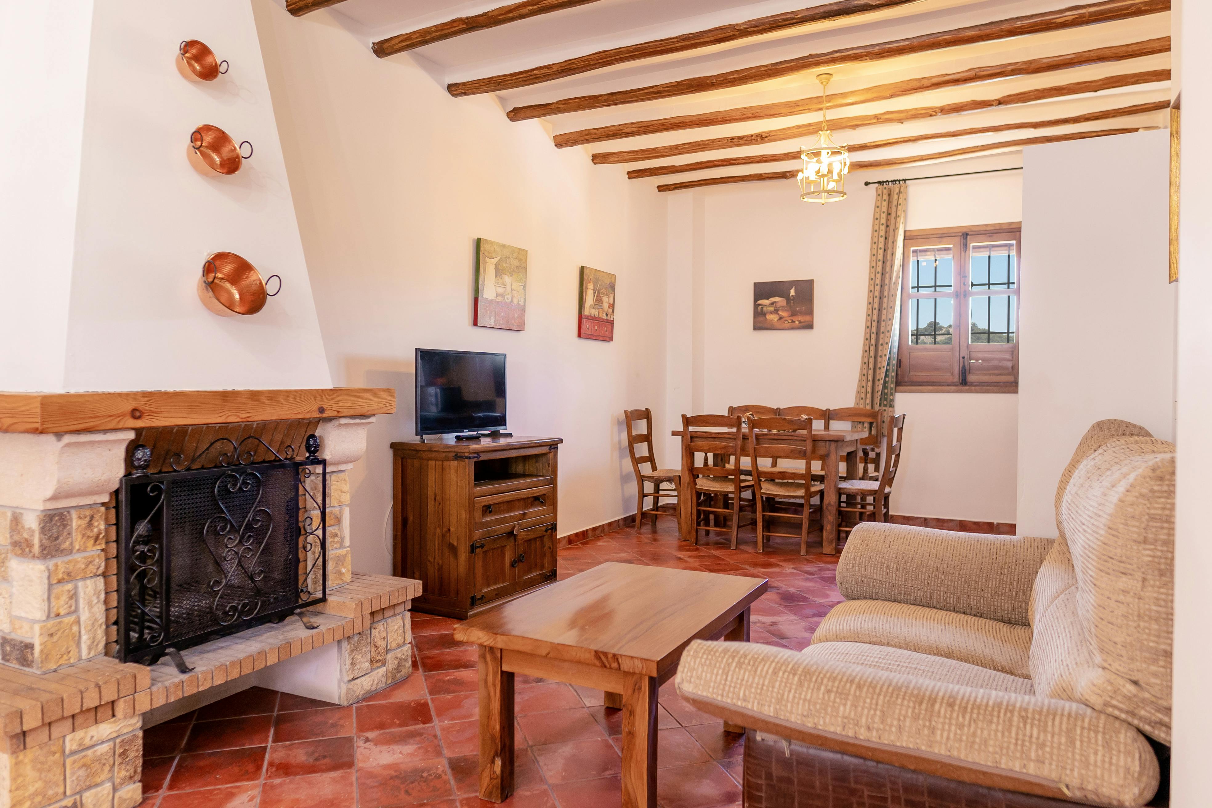 Interior of a holiday apartment showing living area with wooden ceiling beams and tiled floor