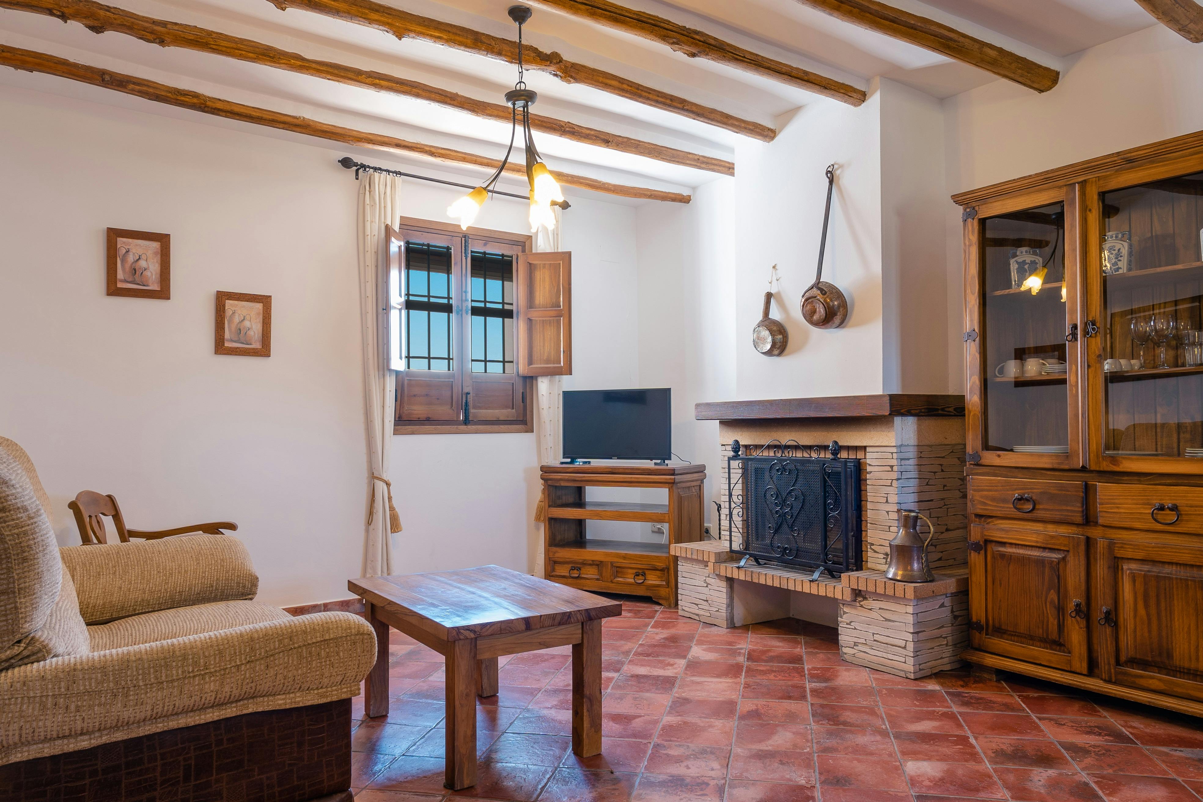 Interior of a holiday apartment showing living area with wooden ceiling beams and tiled floor