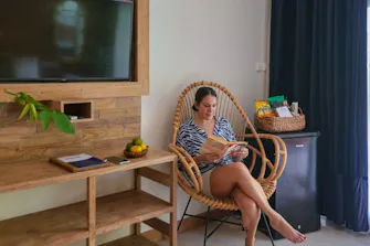 Guest relaxing in a comfortable room at Pesona Beach Resort & Spa, featuring modern amenities, cozy furnishings, and tropical