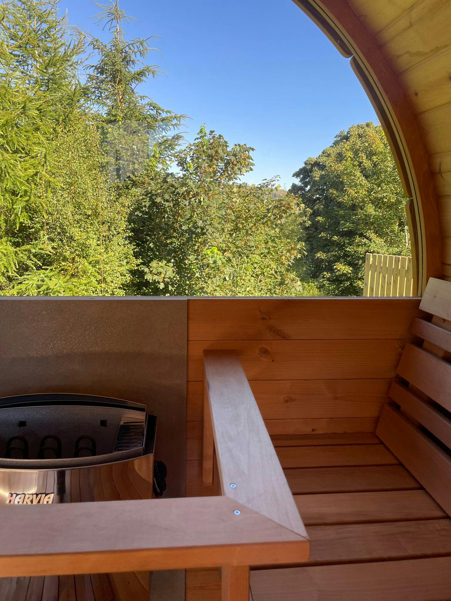 Outdoor barrel sauna at The Cedar Country Hotel, surrounded by trees.