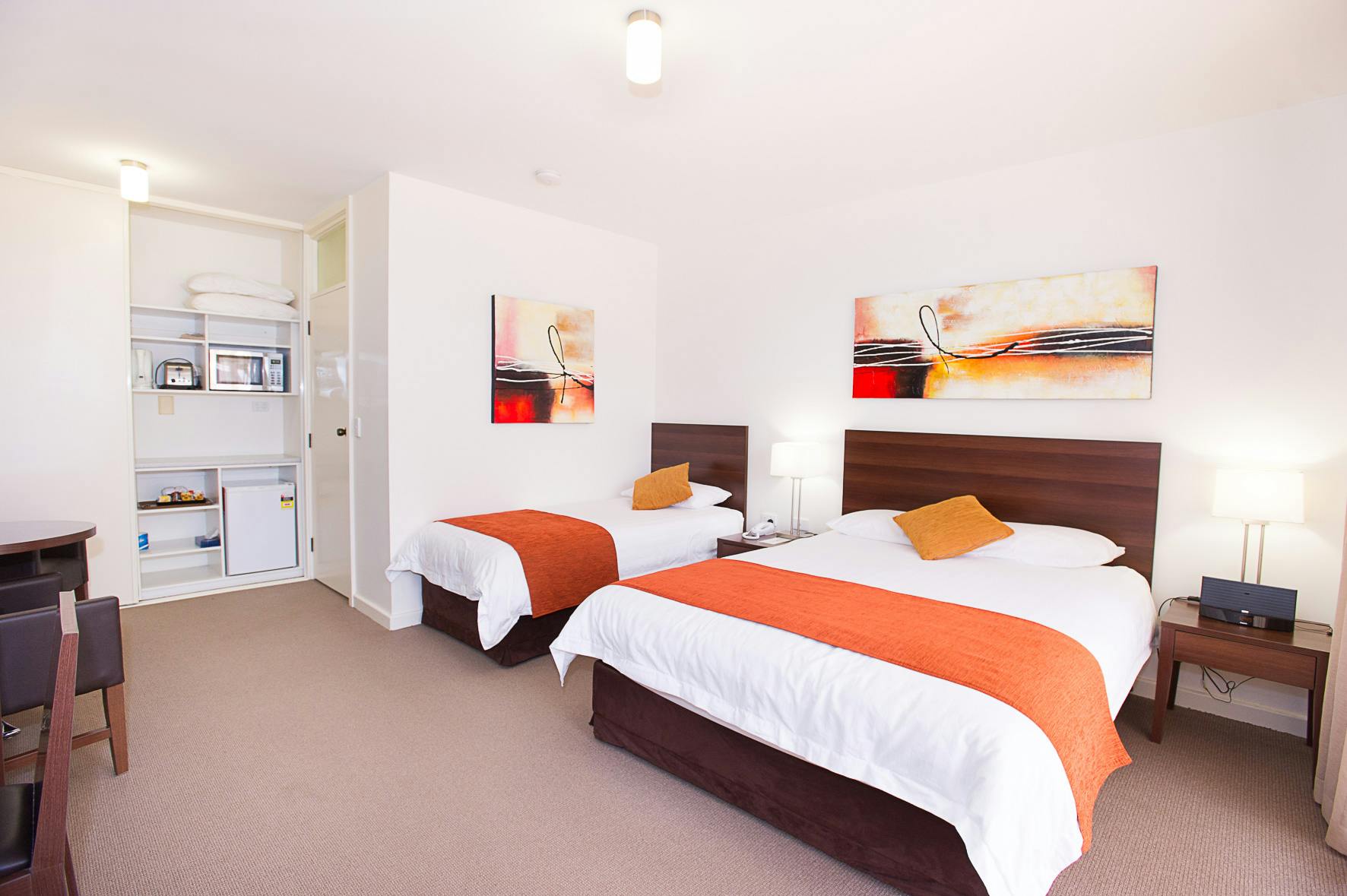 Motel room with double & single beds, microwave, and simple furnishings.