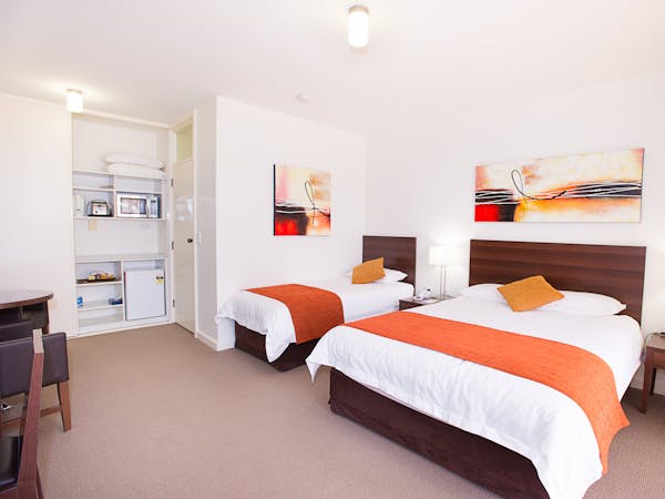 Motel room with double & single beds, microwave, and simple furnishings.