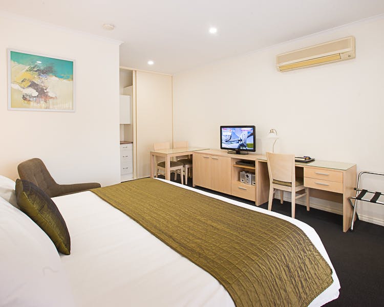 Modern motel room with king bed, desk, and TV.