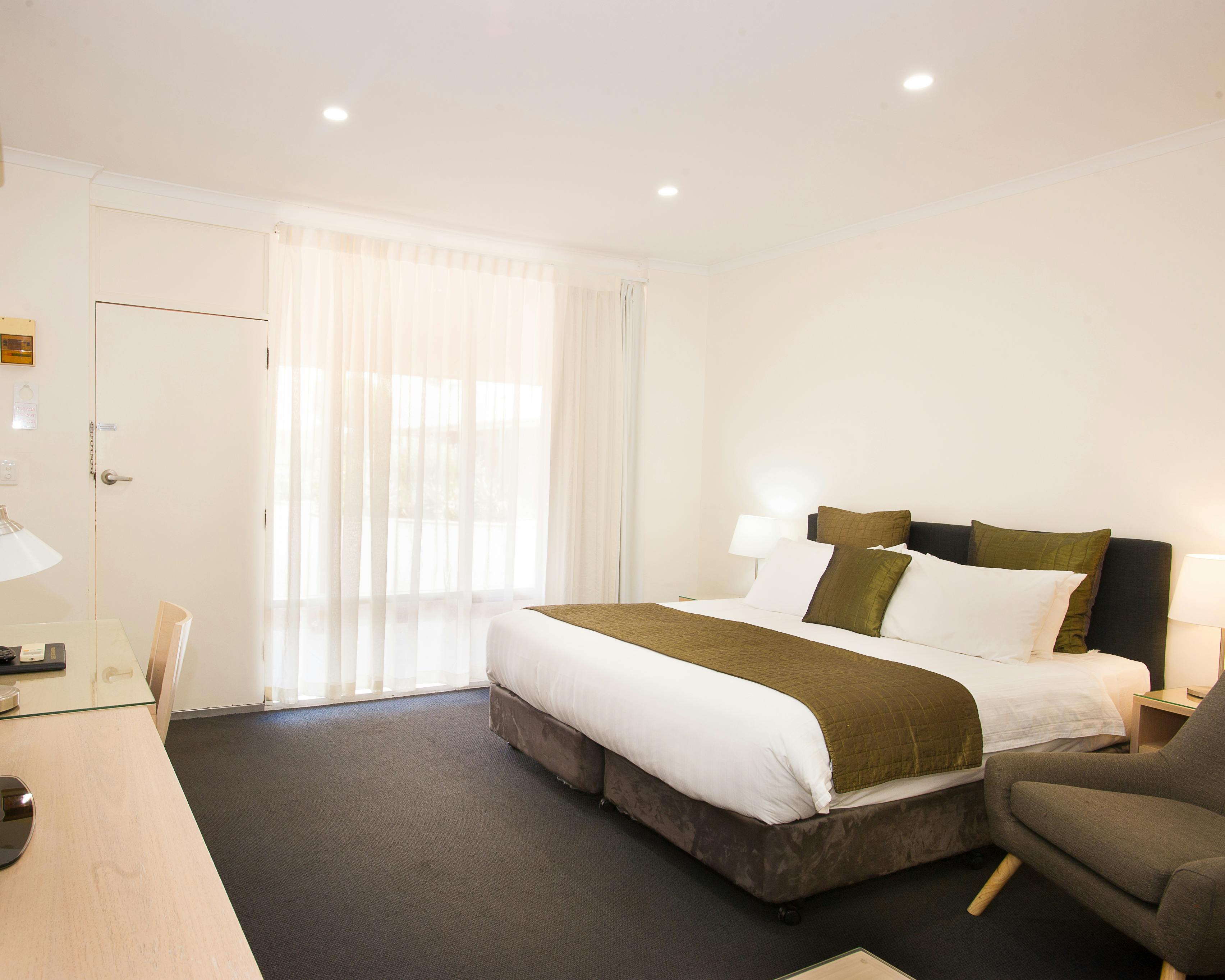 Modern motel room with king bed and sleek design.