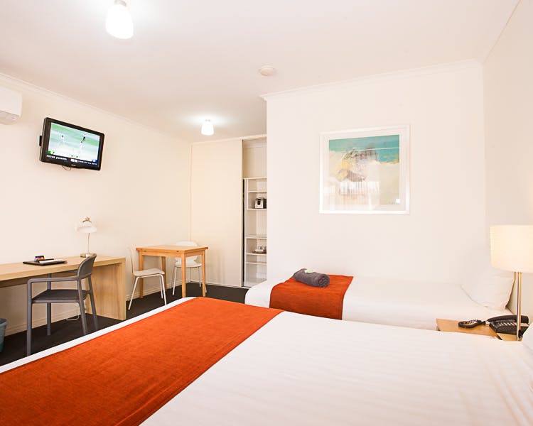 Clean, modern motel room with one double & one single bed & a desk.