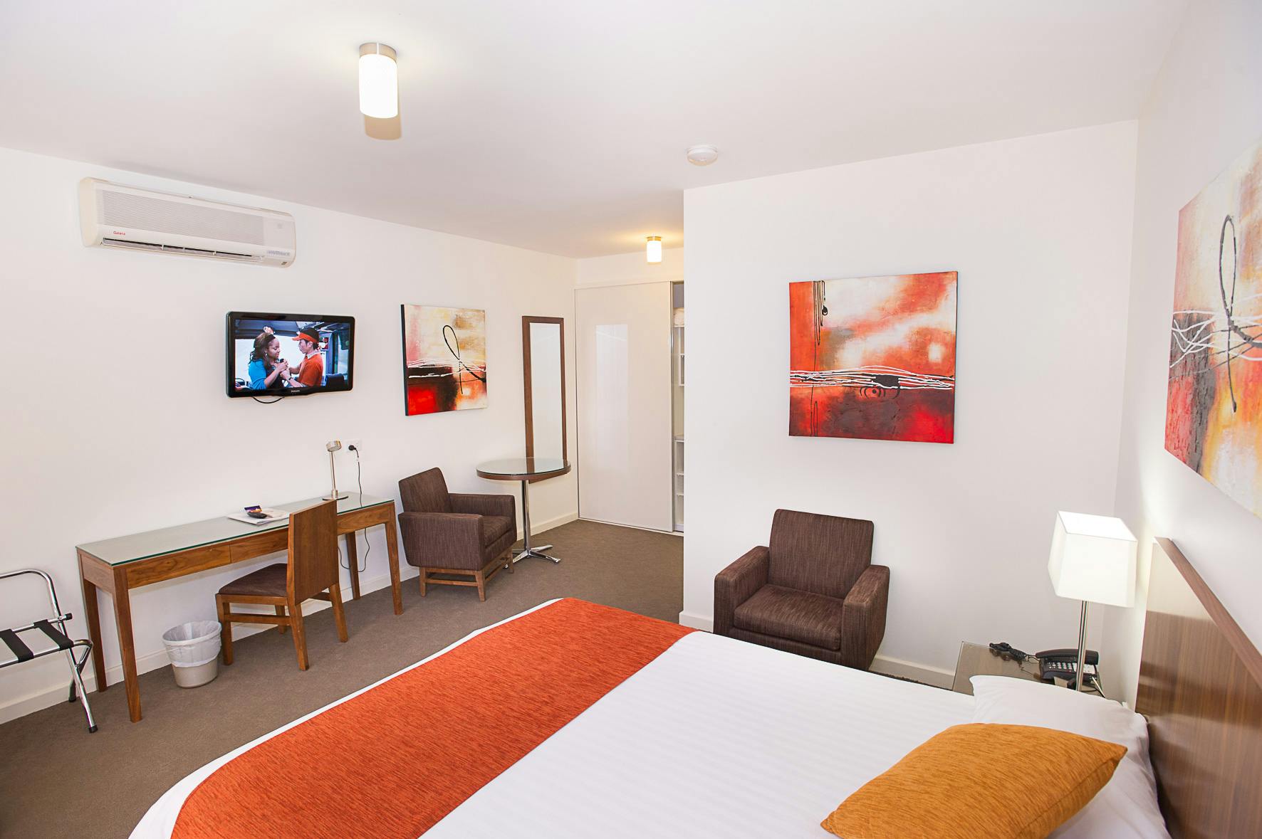 Clean, contemporary motel room with king bed, two armchairs, and a functional workspace.