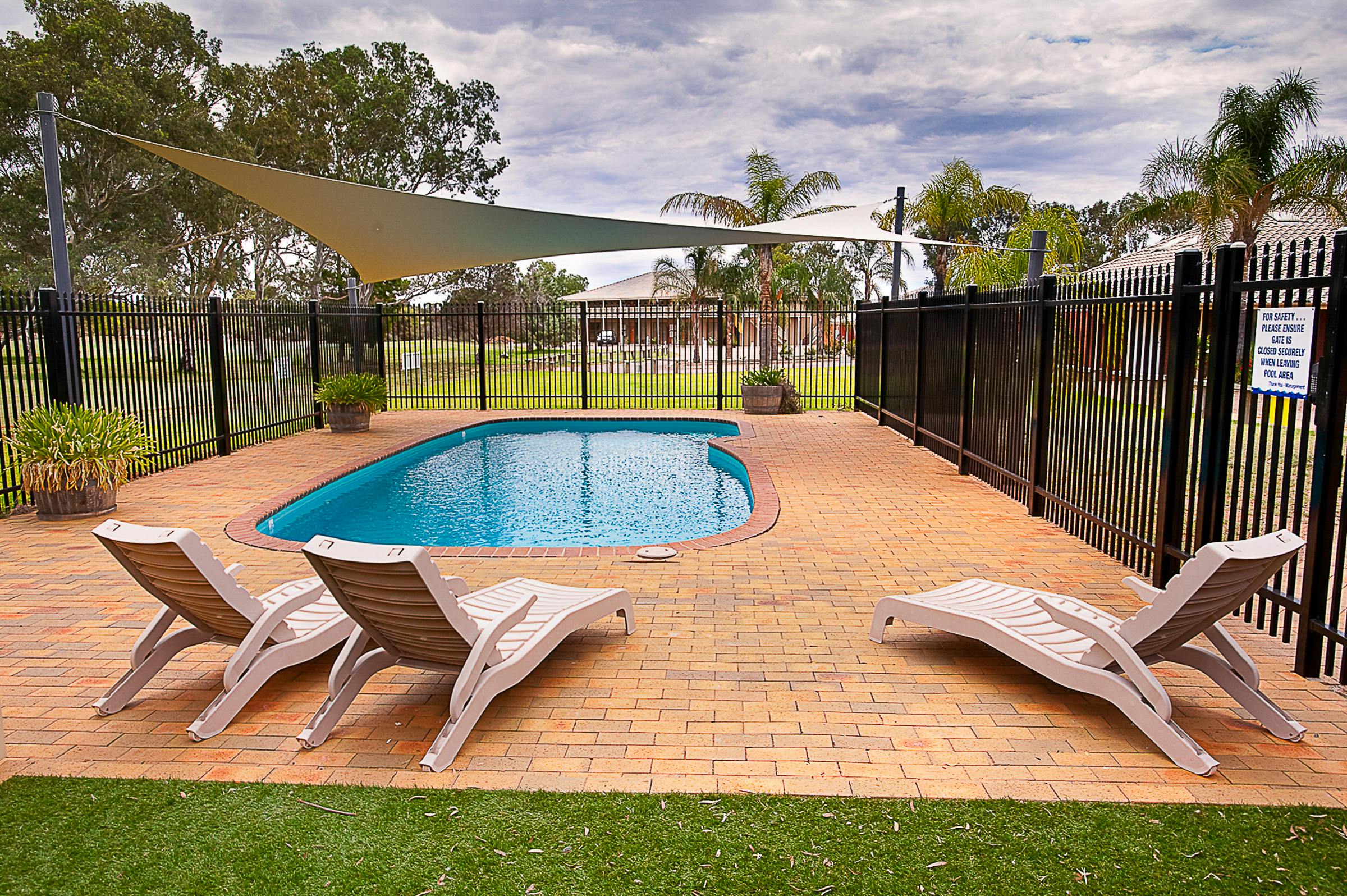 Poolside relaxation at Standpipe Golf Motor Inn. Shade, sun, and lounge chairs await by the cool pool.