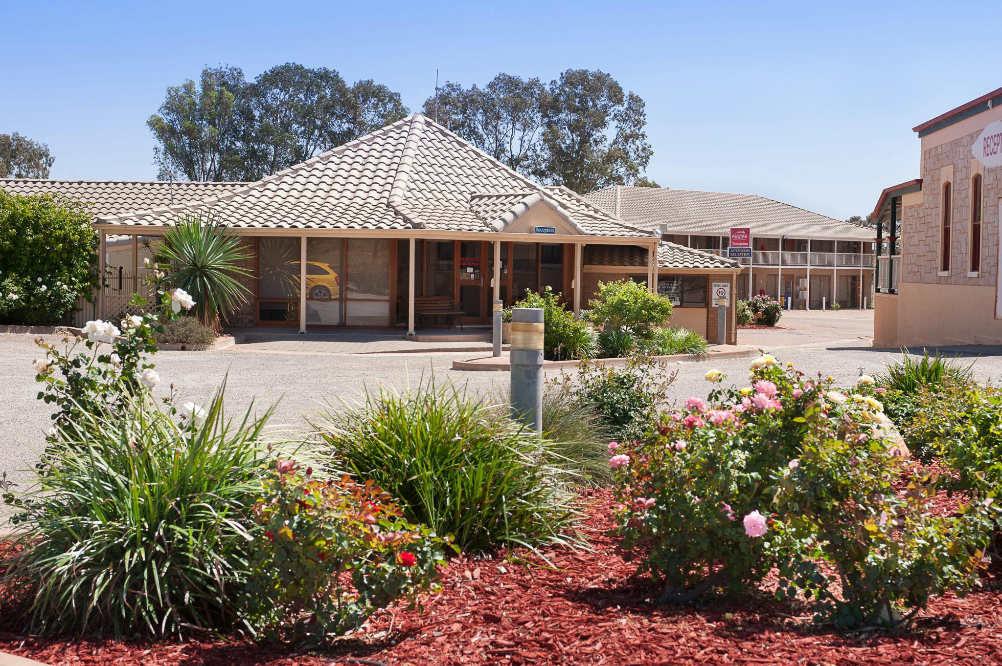 The Standpipe Golf Motor Inn, featuring a single-story building with a brown-tiled roof, surrounded by vibrant flowers and gr