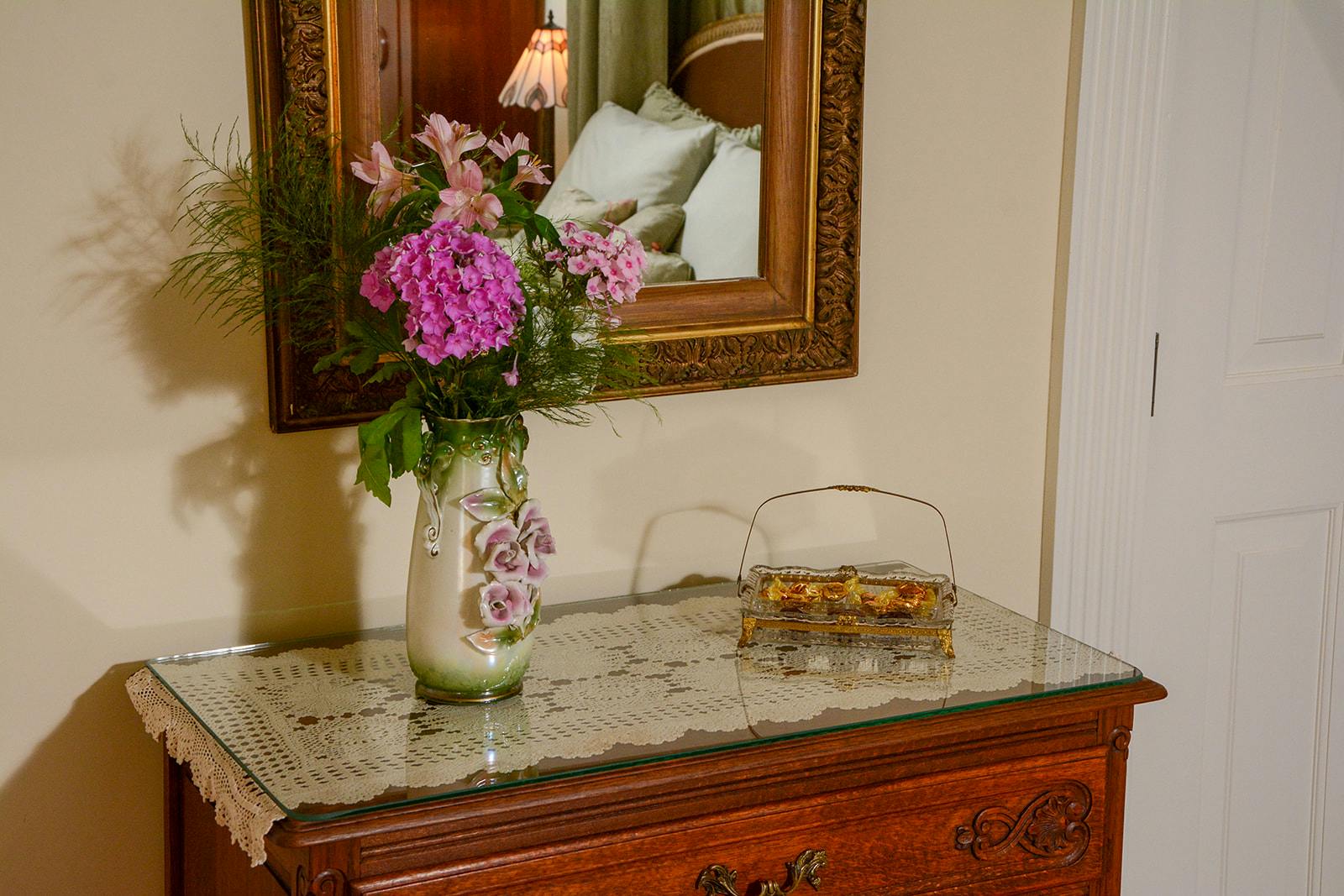 Bureau with a vase of flowers in the Rapunzel Suite.