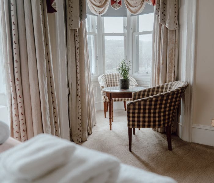 A hotel room with a chair and table, providing a comfortable space for guests to relax and work.