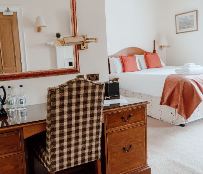 A cozy bedroom with a neatly arranged desk, a comfortable chair, and a inviting bed.
