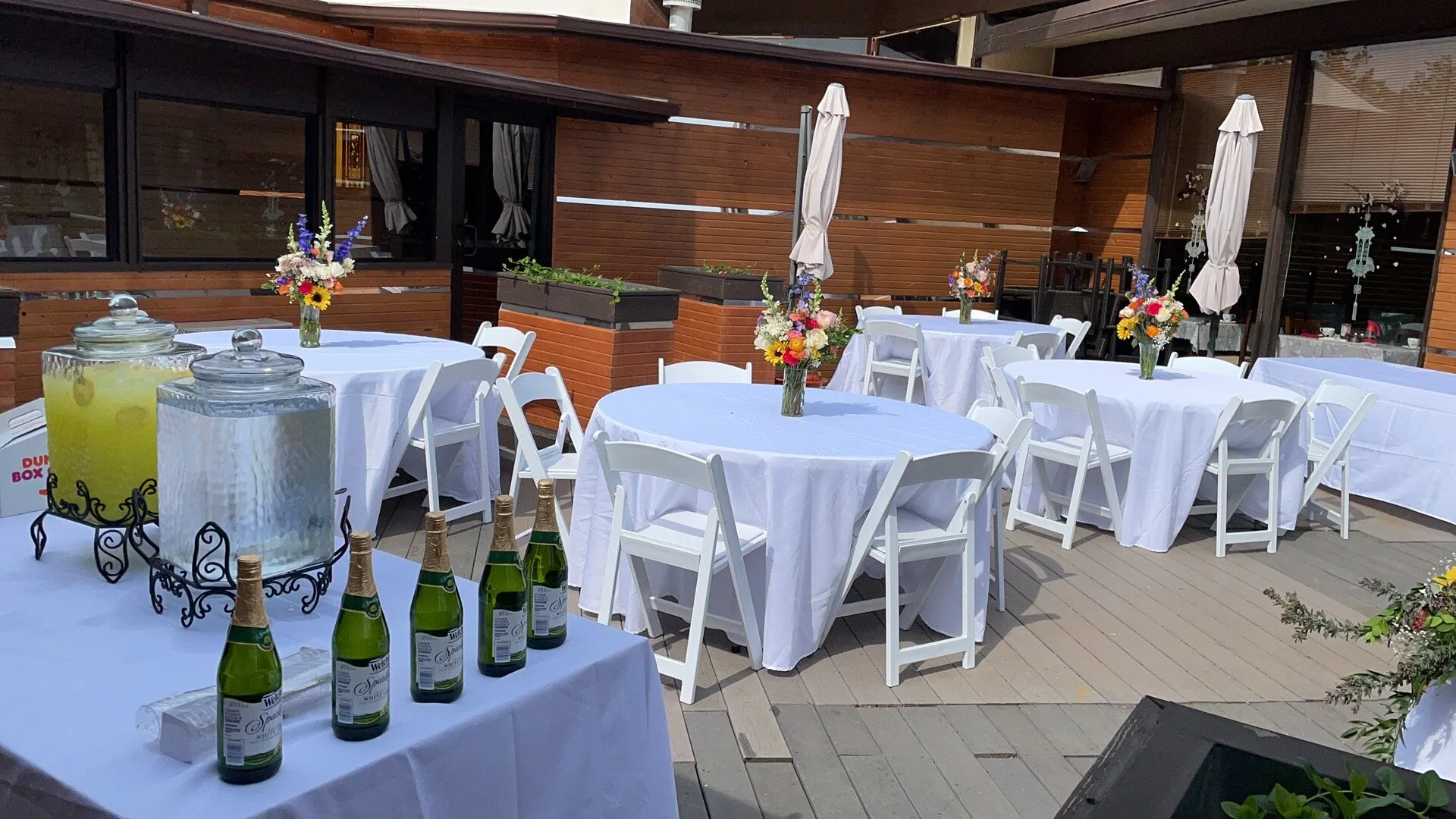 Outdoor reception tables with flowers and beverage station