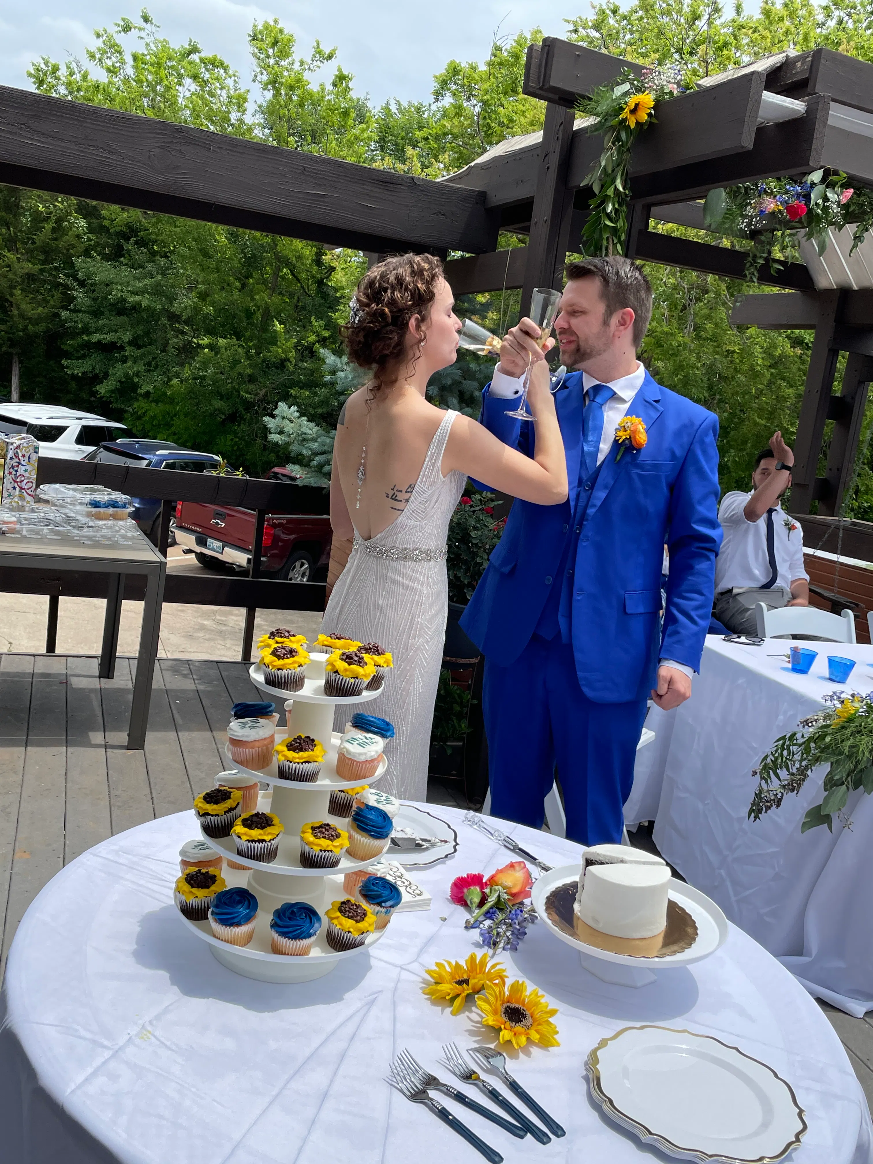 Bride and groom toasting beside their wedding cake and cupcakes