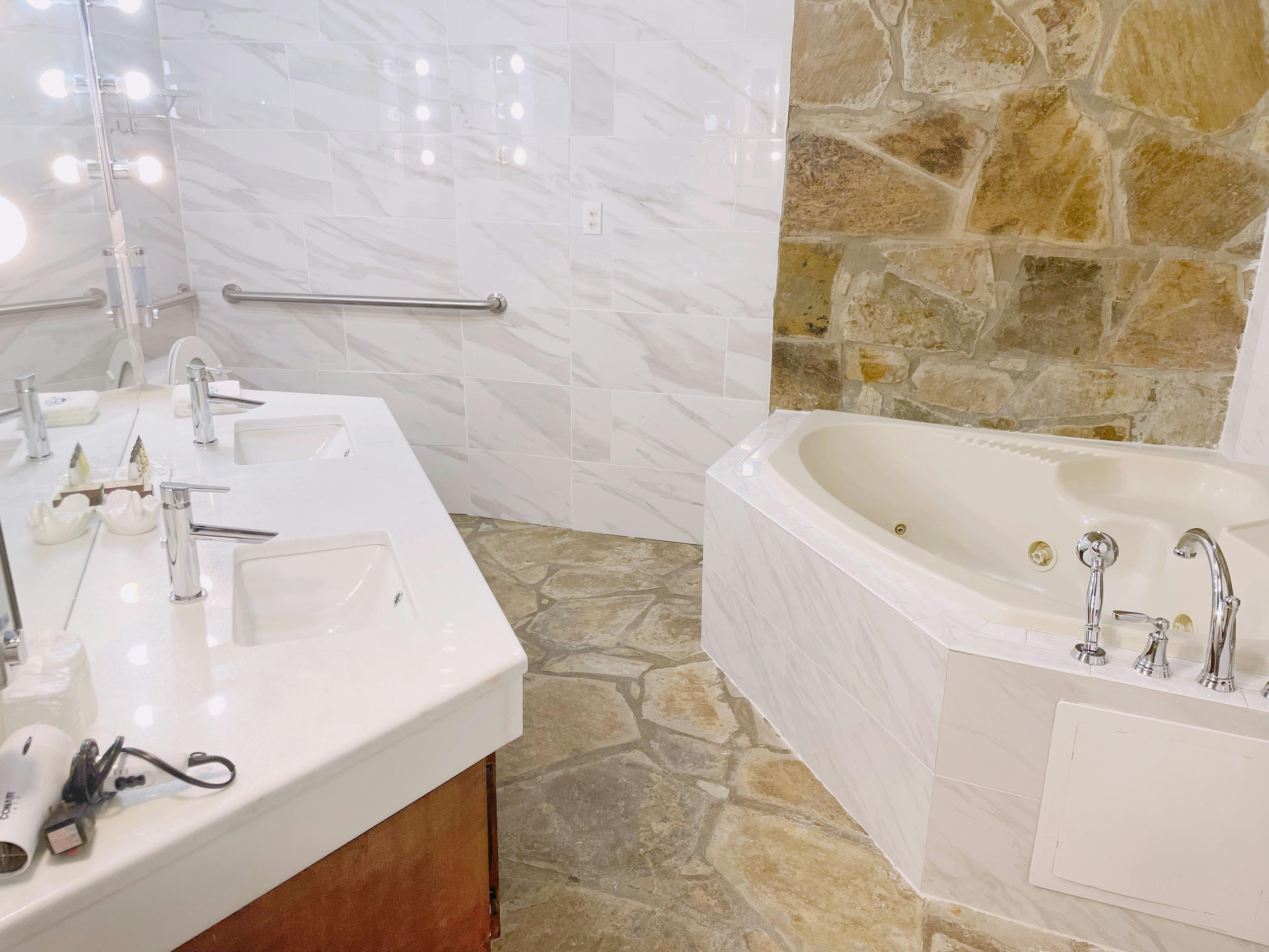 Signature room jacuzzi tub with stone floor and modern vanity