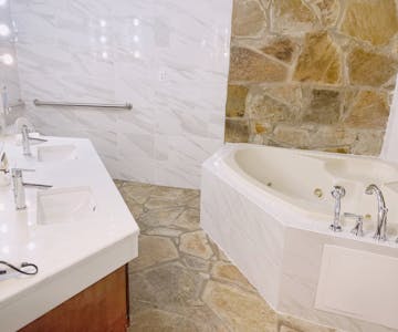 Signature room jacuzzi tub with stone floor and modern vanity