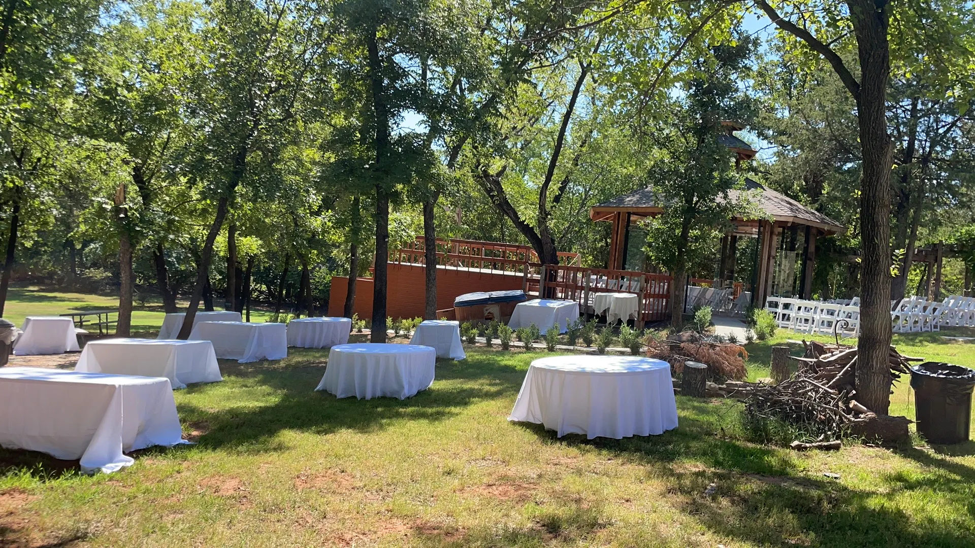 Garden event setup with white-covered tables beside the pavilion