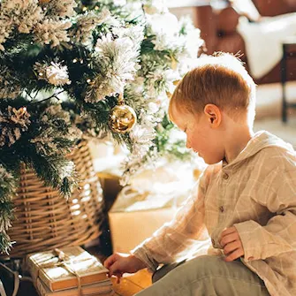 Menino ao pé da árvore de Natal