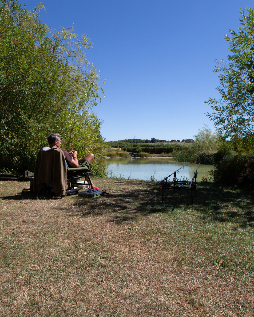 Fisherman at lake, waiting for his catch. Premier Fishing Spots: Panshill's Diverse Fishery Selection in Oxfordshire.