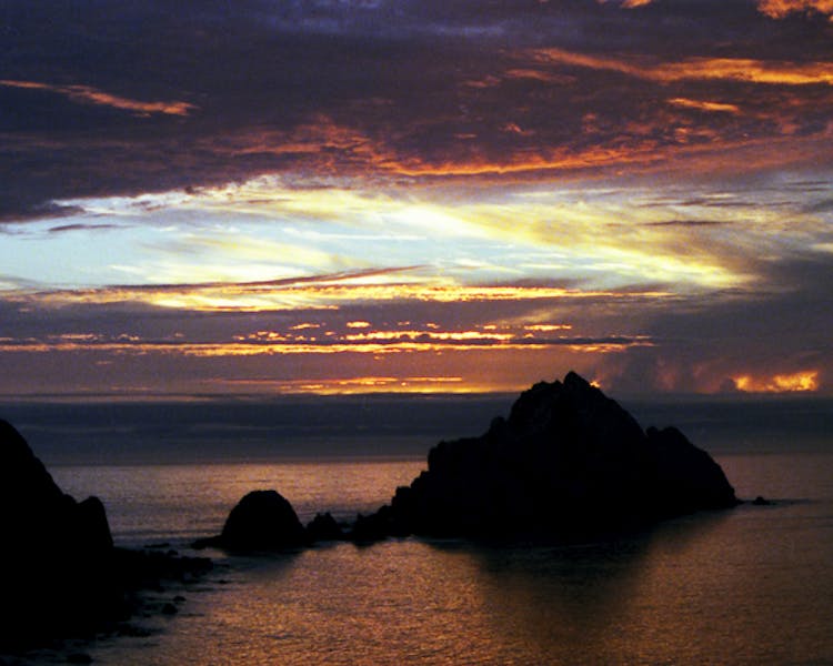 Sunset behind coastal rock formations