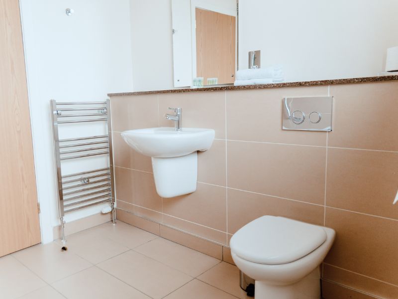 A bathroom with shower over bath amd sink, in modern neutral colours.
