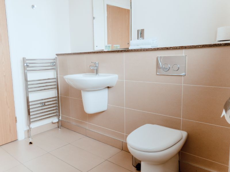 Modern bathroom with sink and toilet in neutral colours.