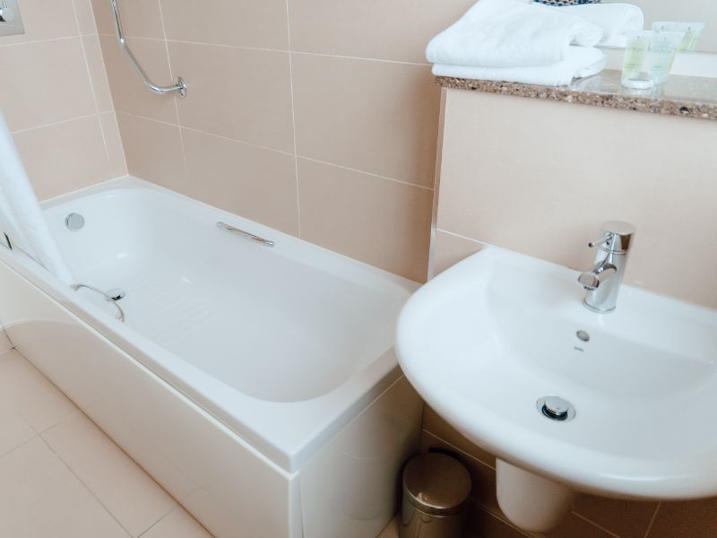 A bathroom with shower over bath amd sink, in modern neutral colours.