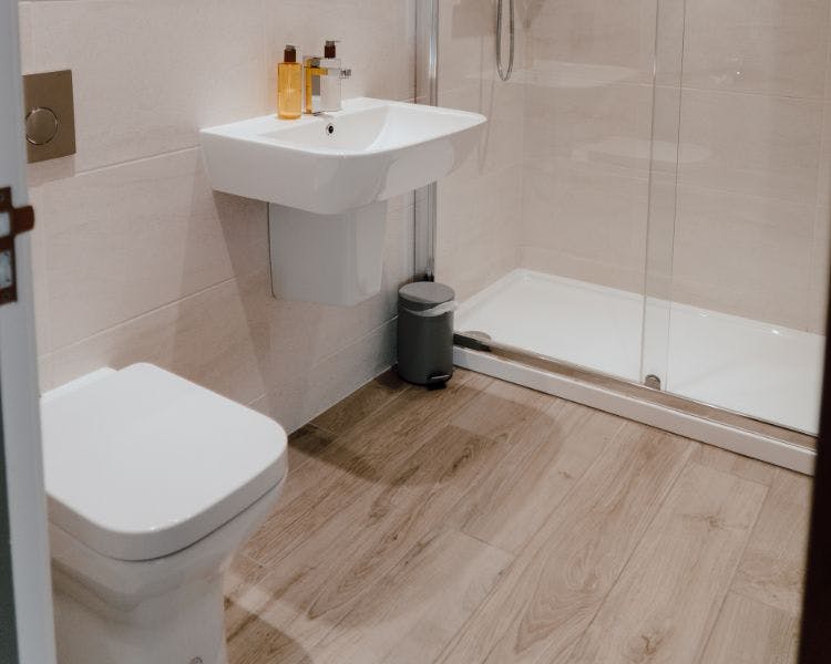 Bathroom with wood effect flooring and white bathroom suite.