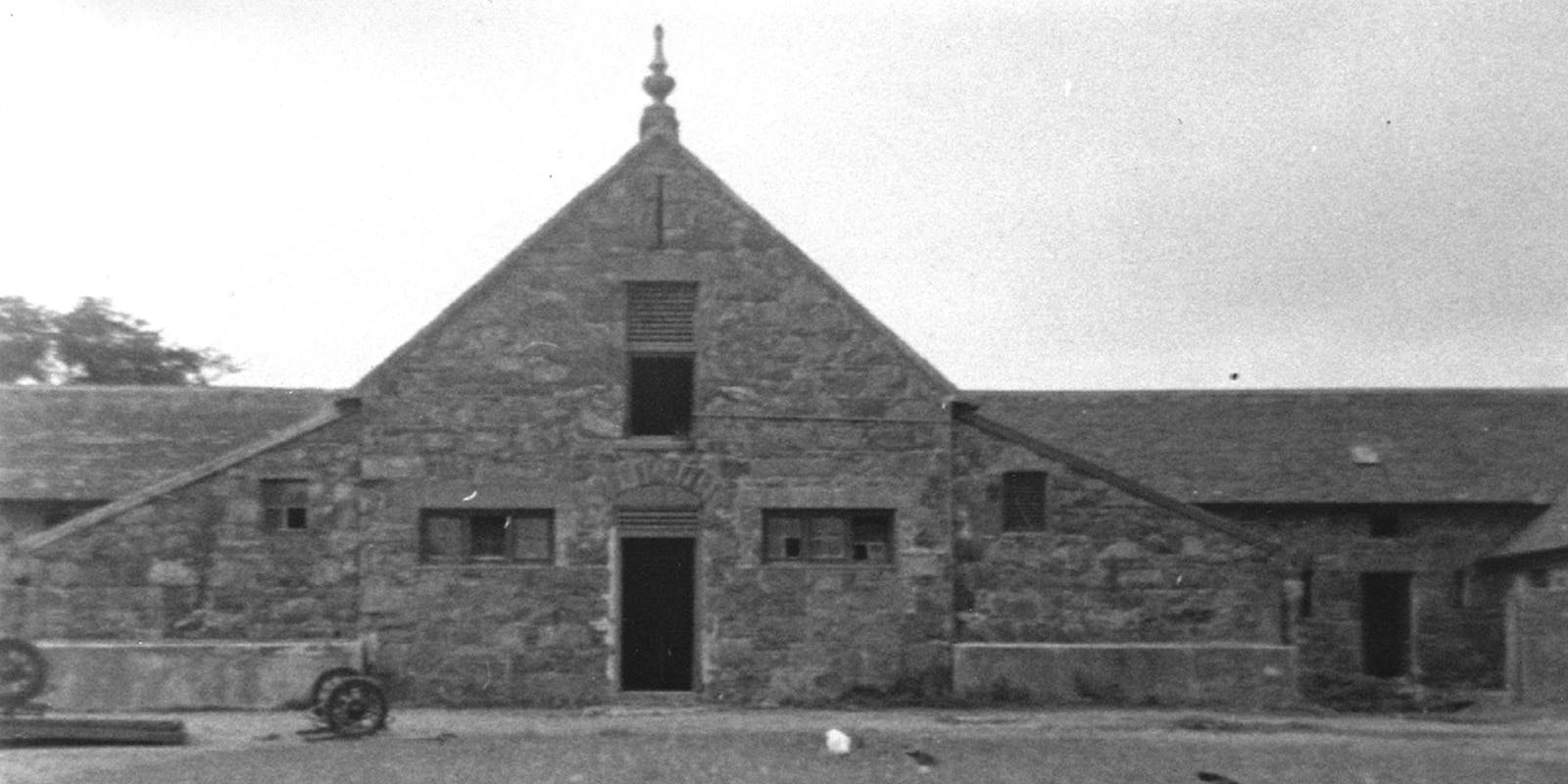 Vintage black and white photograph of a building with a clock tower, identified as Manor Farm on the Isle of Lewis.