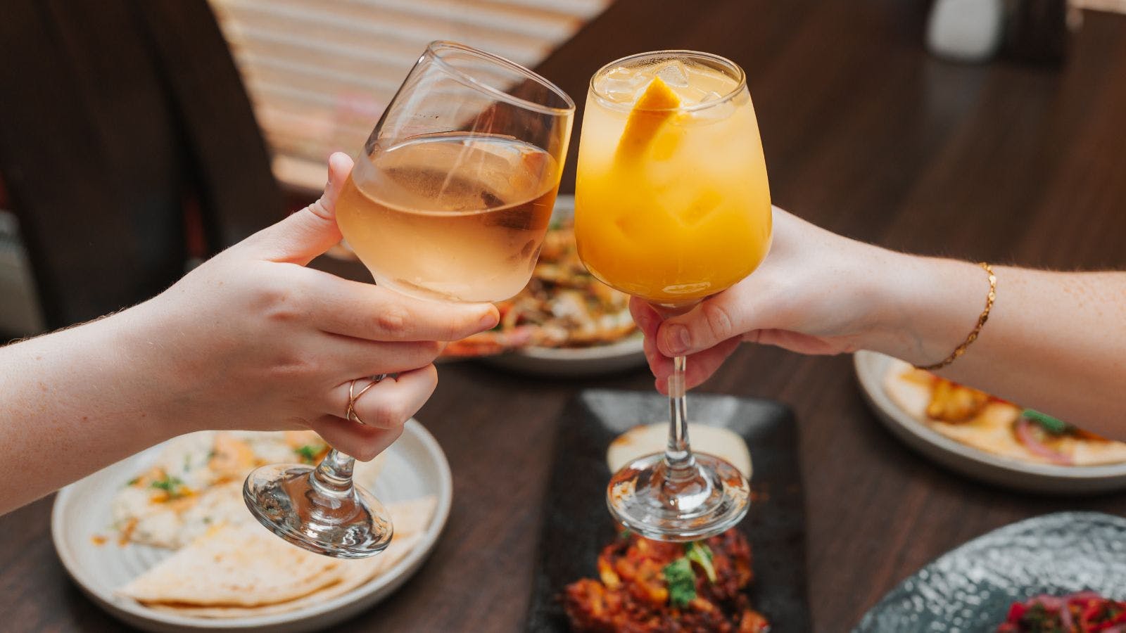 Two people toast with wine glasses over a table filled with food at Cleaver Cabarfeidh Hotel.