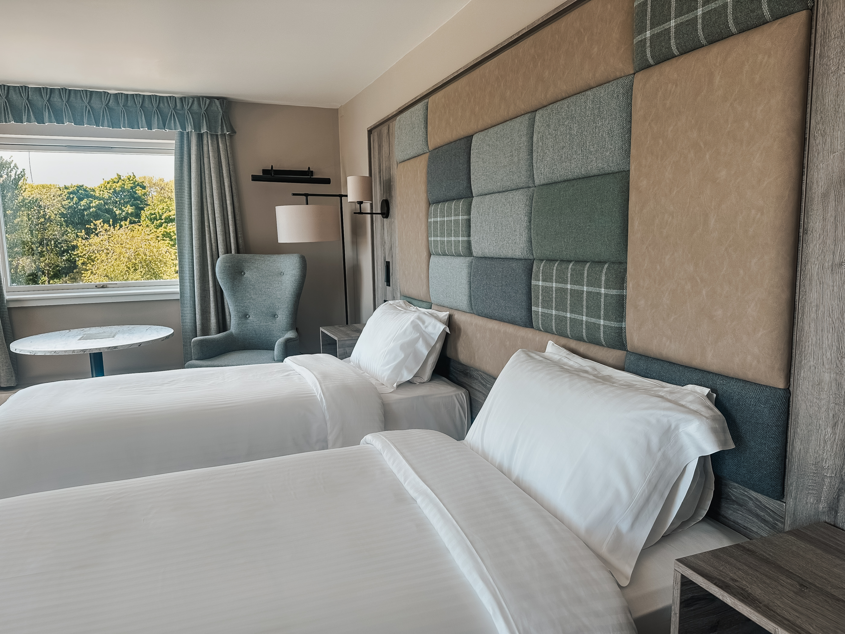 Executive twin room at Cabarfeidh Hotel featuring two beds and a large window with natural light.