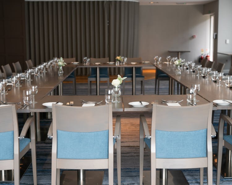 A spacious table with several blue chairs arranged around it, ideal for dining or discussions.