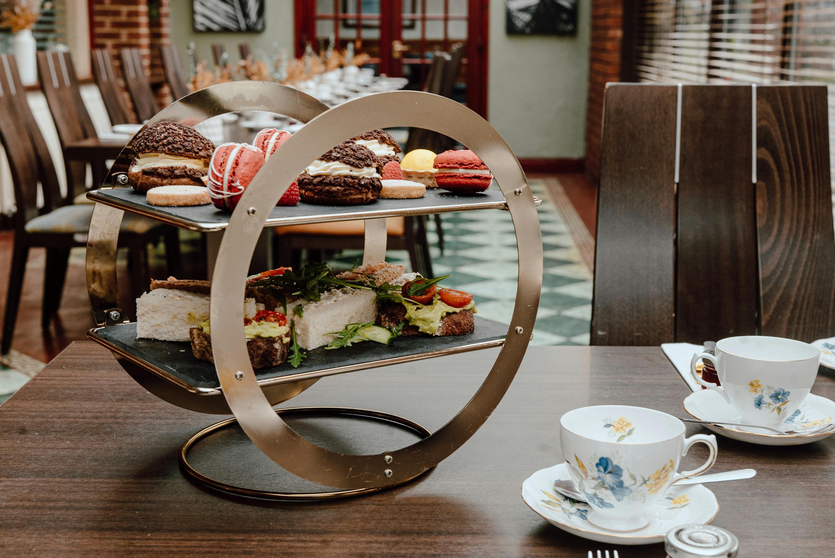 A cosy afternoon tea at Cabarfeidh Hotel, with a table displaying a tray of food and a cups with tea and coffee.