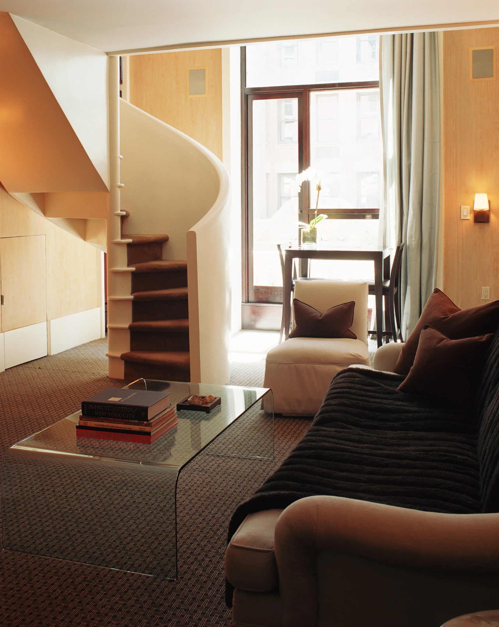 A lobby with a spiral staircase, sofa, coffee table and chair