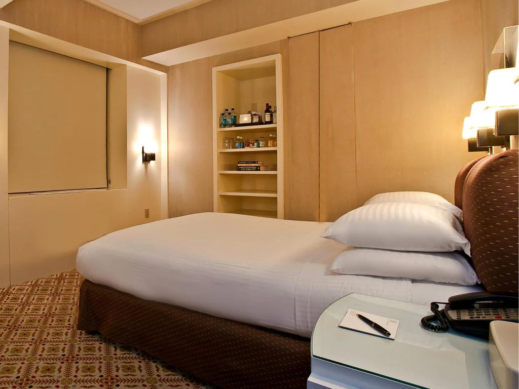 A hotel room with a bed, desk, and closet.